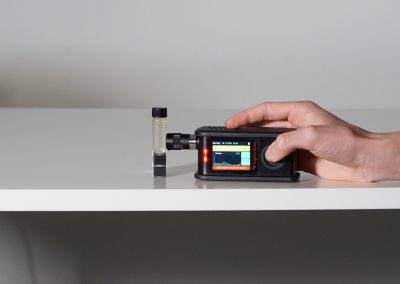 miniRaman spectrometer analyzing small sample container on table